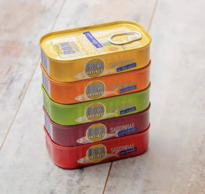 Stack of colorful tins with visible branding on a light wooden surface